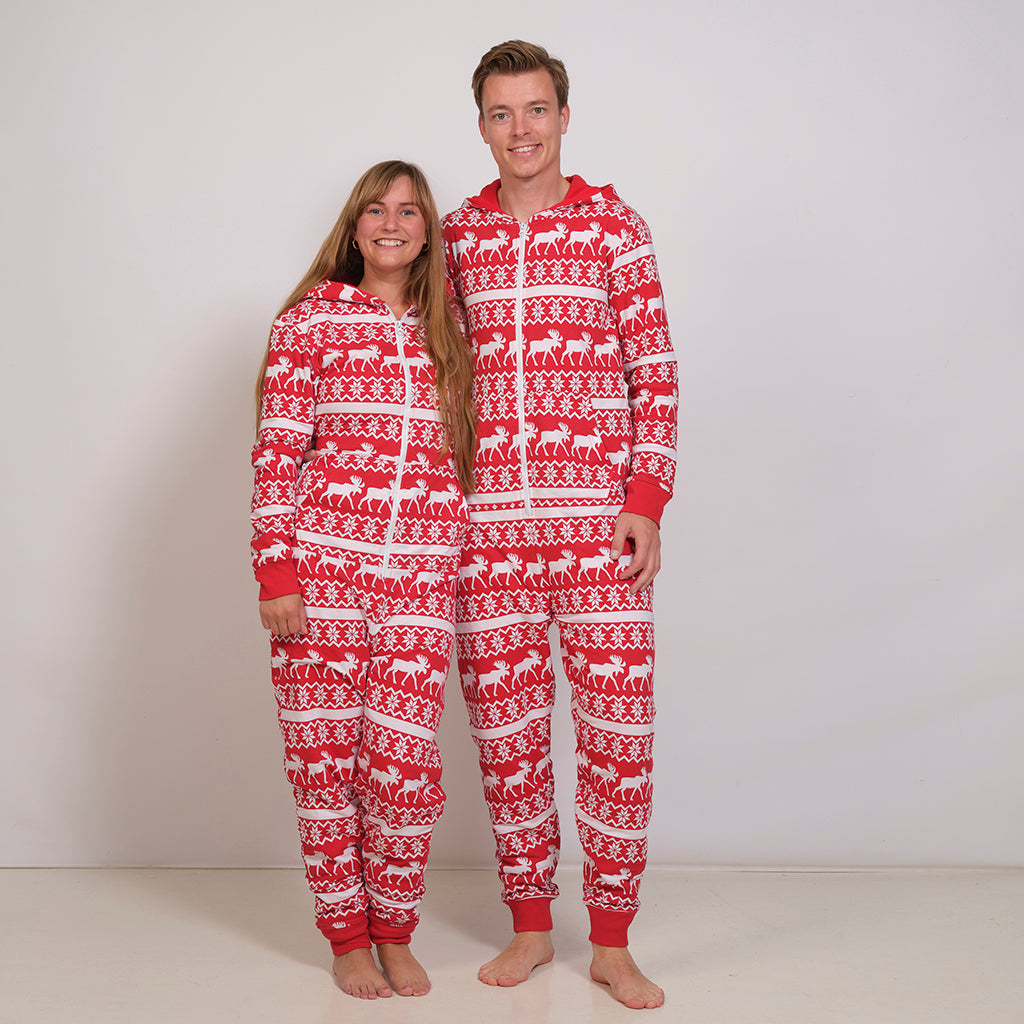 En mand og en dame står sammen og er begge i klædt et røde julejumpsuit.