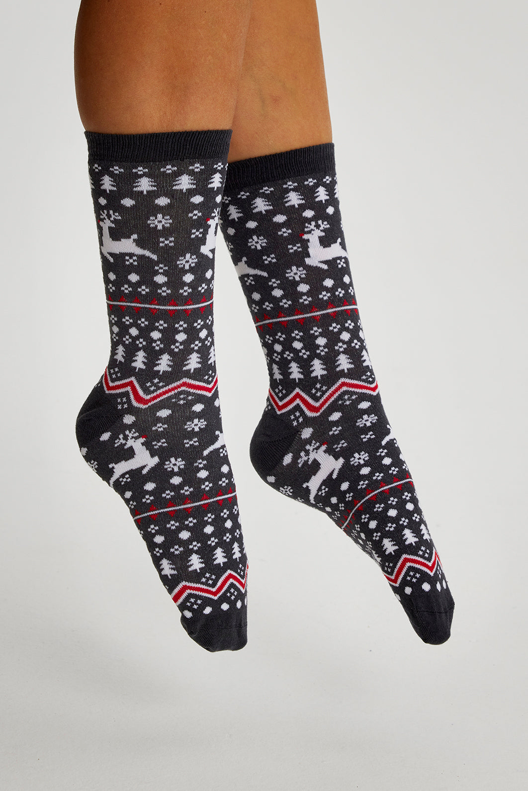 Een paar benen met een paar zwarte kerstsokken met rendieren erop.